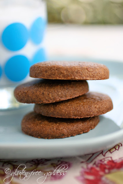 Vegan gluten free gingersnaps in a stack with a glass of cold coconut milk