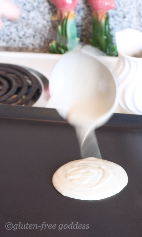 Pouring gluten-free pancake batter onto the griddle.