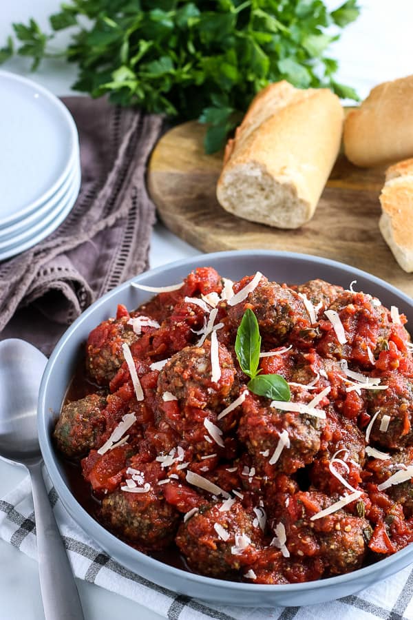 a big bowl of meatballs with bread in the background