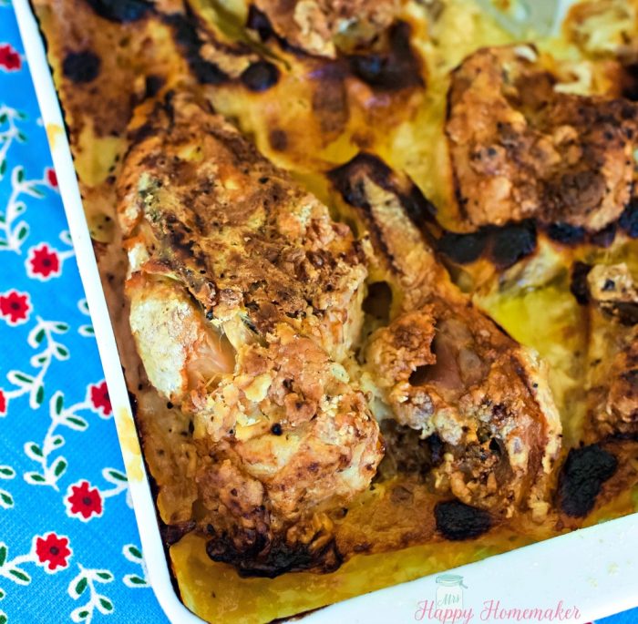 chicken baked in butter and cream in a casserole dish on a blue and red print cloth