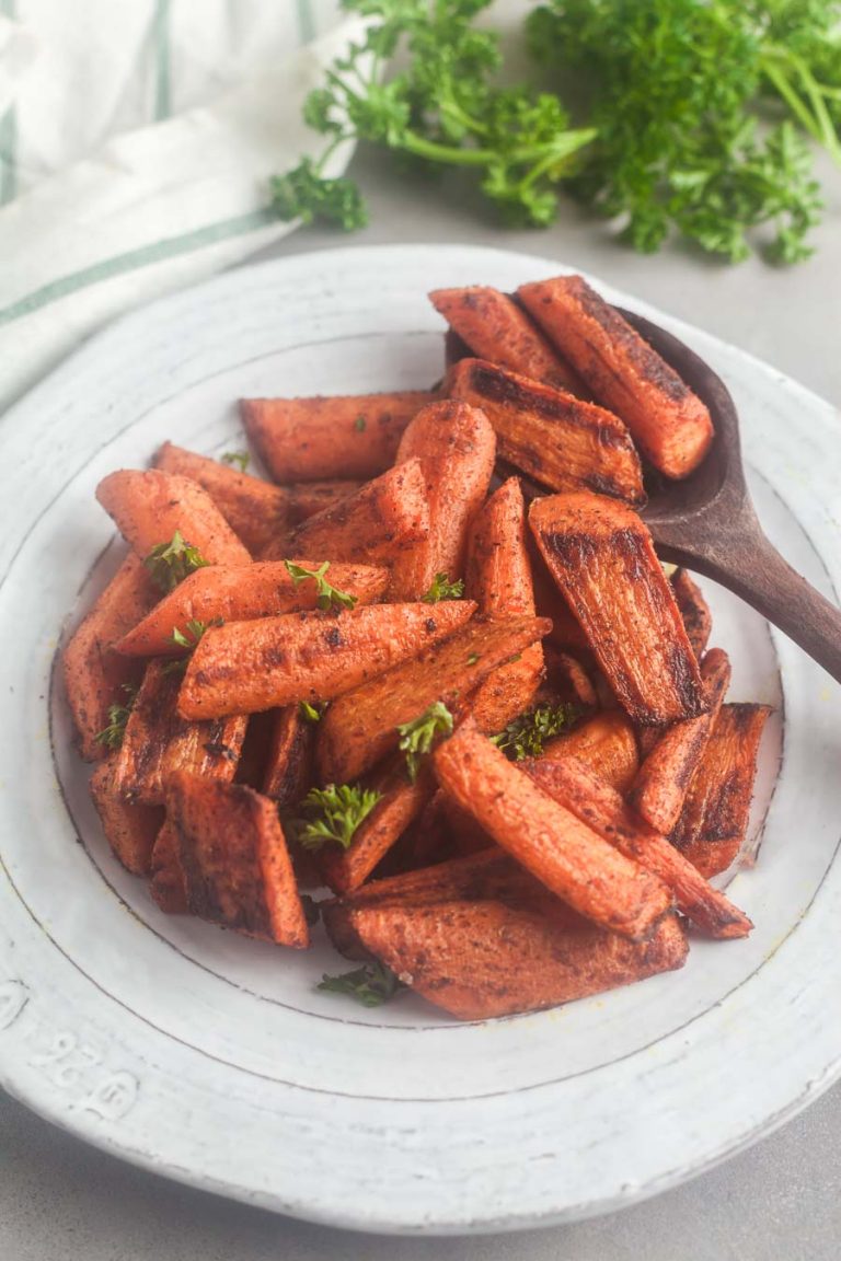 A serving bowl of roasted carrots with ras el hanout and parlsey
