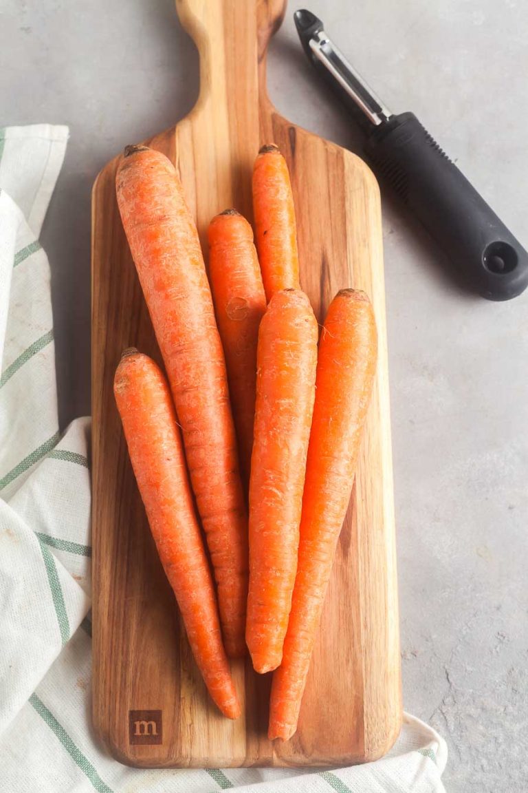 Carrots on a cutting board, ready to be peeled