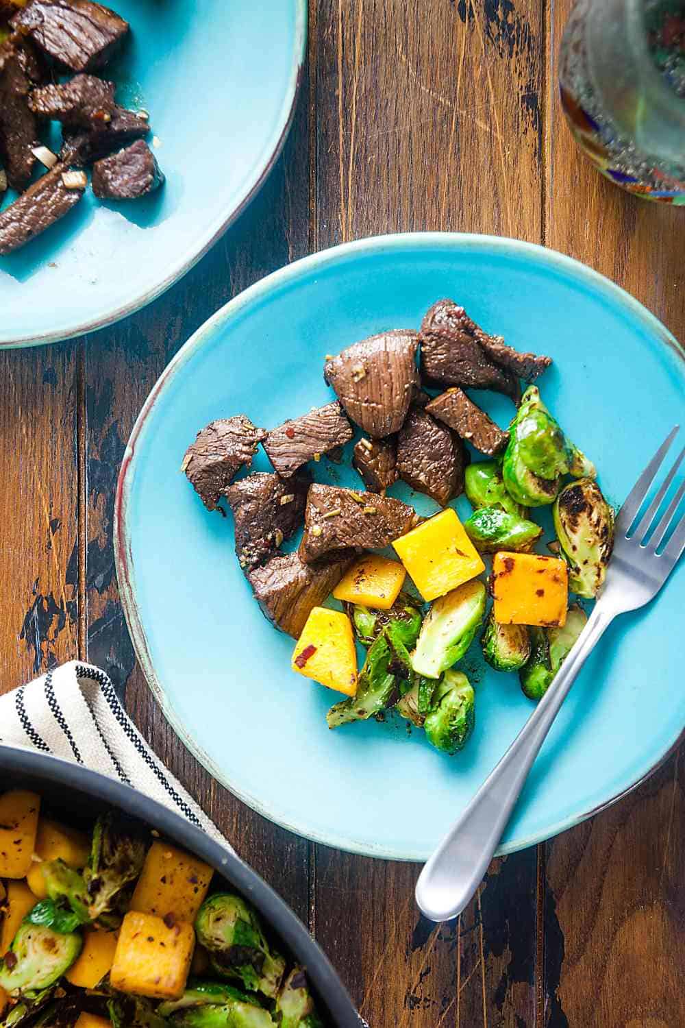 rosemary-balsamic marinaded steak tips with butternut squash and Brussles sprouts on a plate