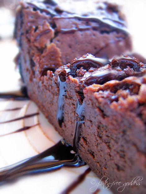 A slice of gluten-free flourless chocolate cake with chocolate sauce.