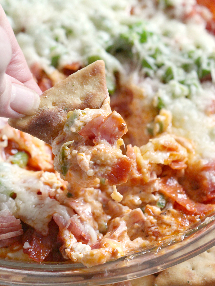 Pepperoni Pizza Dip recipe that is easily made with cream cheese, pizza sauce, pepperoni, cheese and all of your other favorite pizza toppings! This delicious appetizer recipe is fast, easy and is always a hit at parties, game day gatherings and family dinners too.