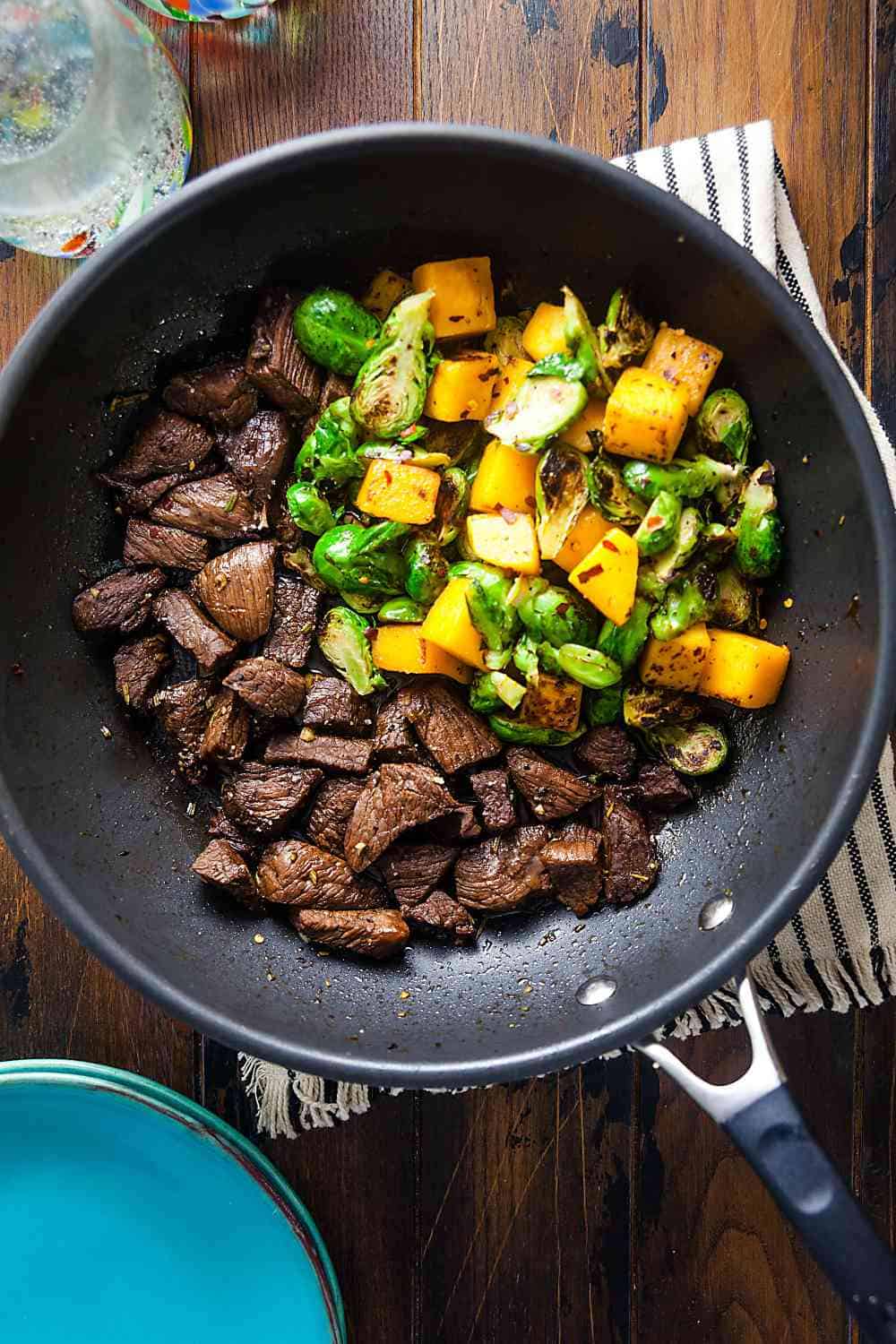 steak tips, butternut squash, and Brussels sprouts in a skillet